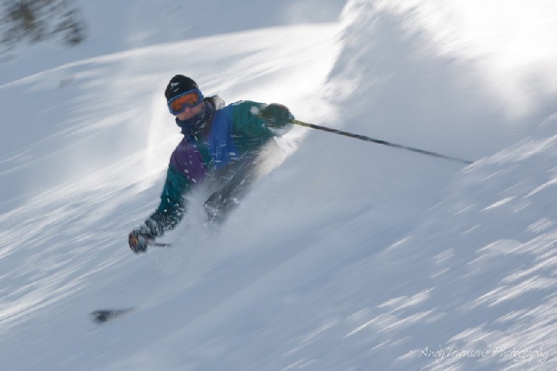 Soft powder sprays when a telemark skier turns in great snow conditions.