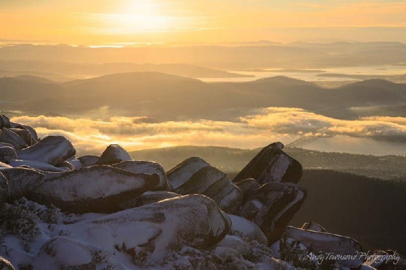 Snow lined boulders sit above a view over a misty Derwent River.
