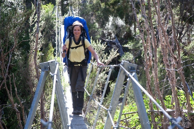 A walker crossing a suspension bridge leaving the Labyrinth area on Tasmania's Overland Track.
