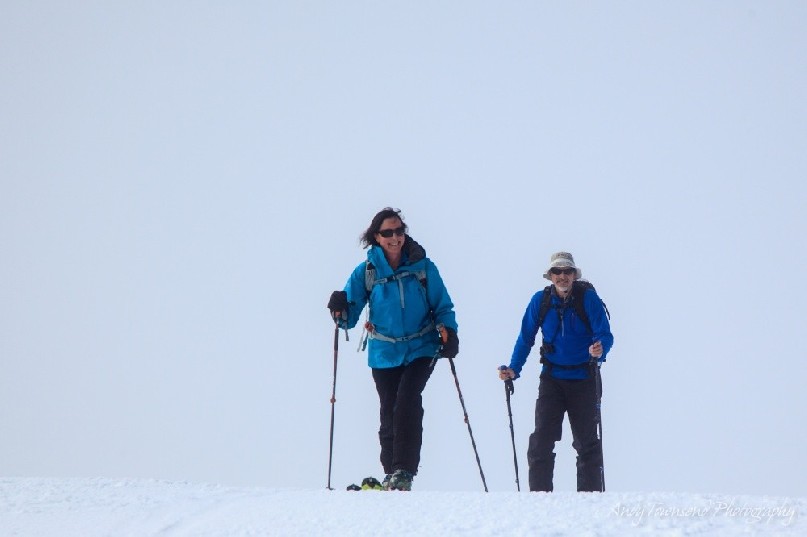 Two backcountry skiers finishing the final ascent to the ridgetop as cloud starts to move in.
