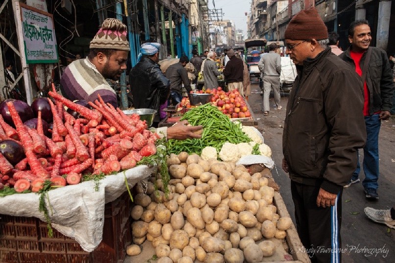 A man buys potaoes at a street stall.