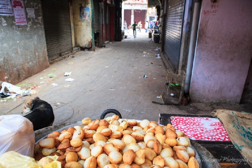 A pile of street food sits ready for customers at the end of a back alley.