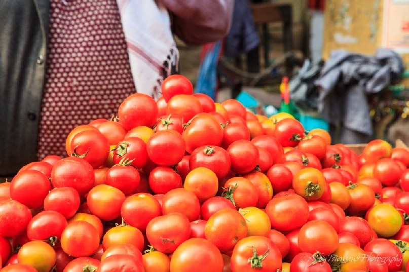 A large stack of tomatoes at a wholesale vegetable market.