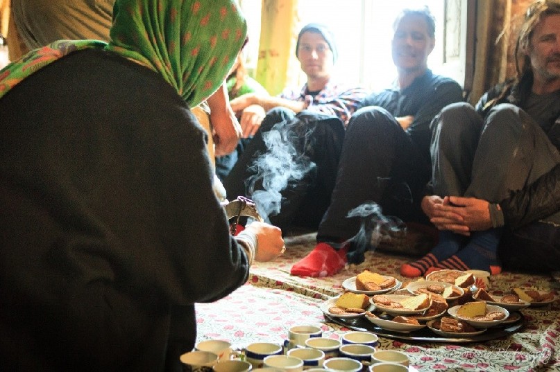 A lady pours sweet Kasmiri tea for a group of skiers in Drung village.