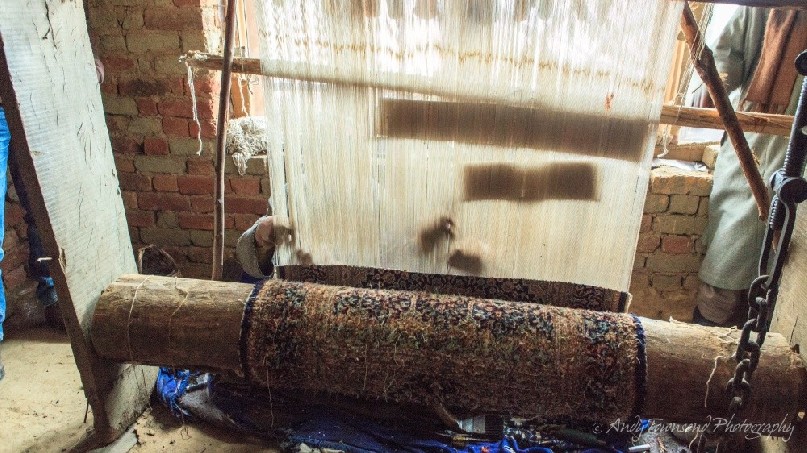 Two men work side-by-side weaving thread together to create a silk carpet - a 6 to 12 month process for one carpet.