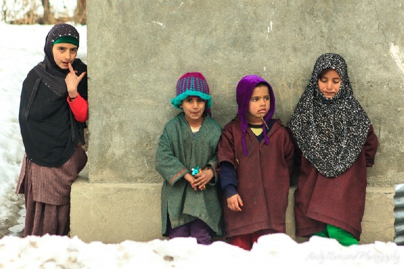 Four children leaning against a house wall in Drung village.