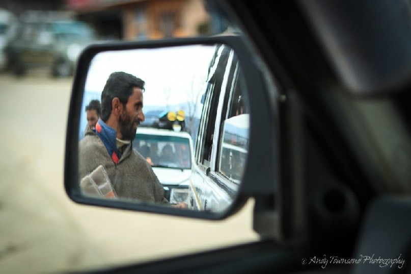 A Targmarg villager stops to sell his wares next to a vehicle window.
