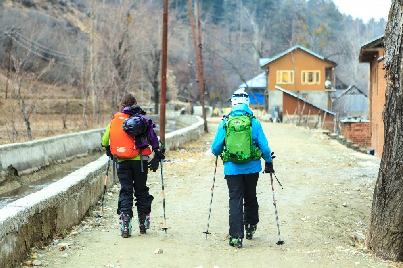 Two female skiers walking along a dirt track between Drung and Tangmarg villages.