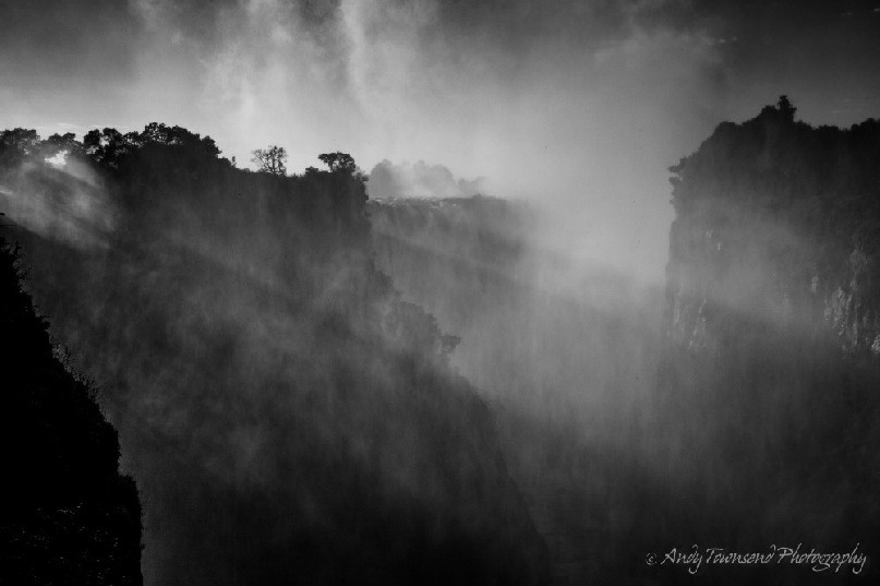 Sunlight filters through the mist and spray from Victoria Falls.