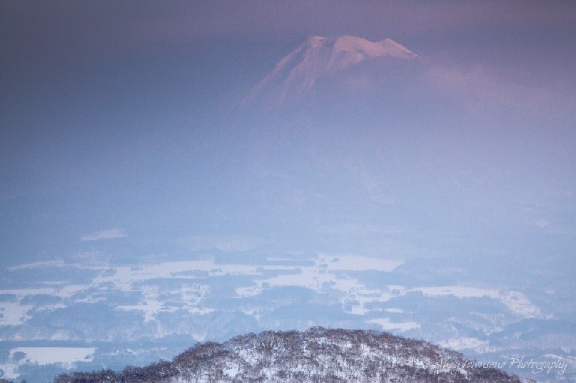 As a light mist decends into the valley, the distant summit of Mt Yotei catches the last light of the day